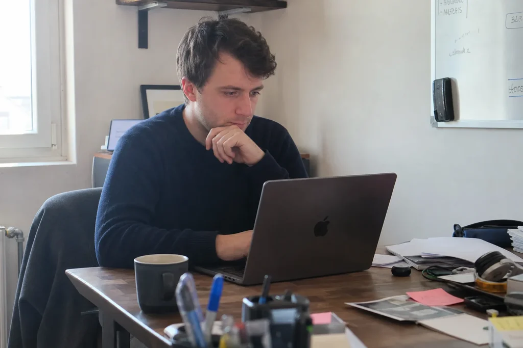 Person som sitter vid skrivbord och utforskar digitala verktyg för företag på sin laptop i ett vardagligt kontorsrum.