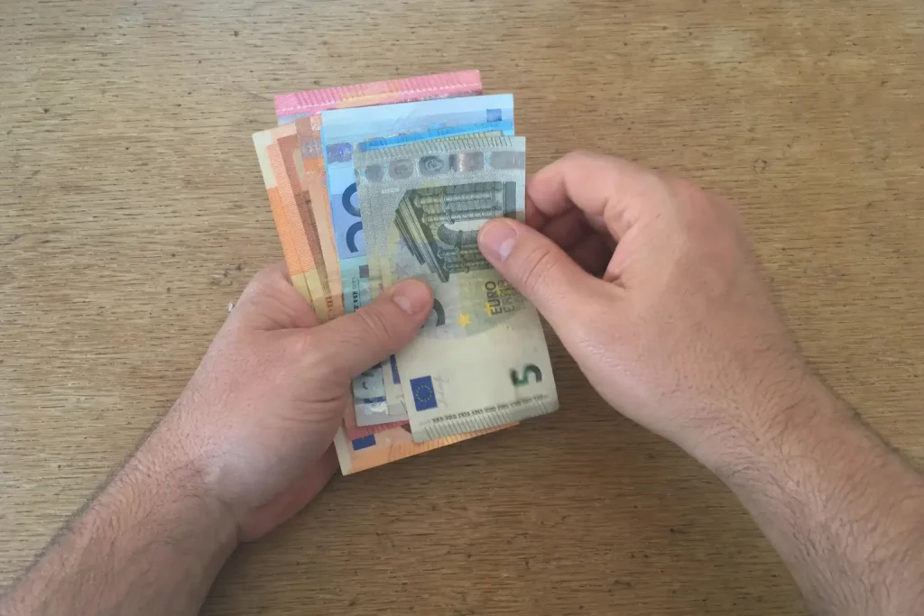 Händer som räknar eurosedlar på ett träbord, relaterat till Daniel Ek-bolag går in i lånesatsningen Float: