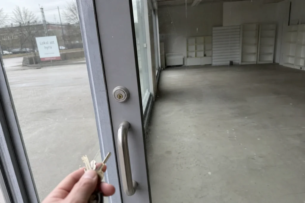 En hand med nycklar utanför en låst dörr till en tom lokal att hyra, kopplat till att bilmärke förlorar 761 000 kr per elbil.