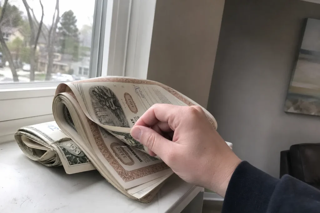 En hand bläddrar i en finanstidning vid ett fönster, i samband med nyheten att EA säljs till Saudiarabien nästa vecka.