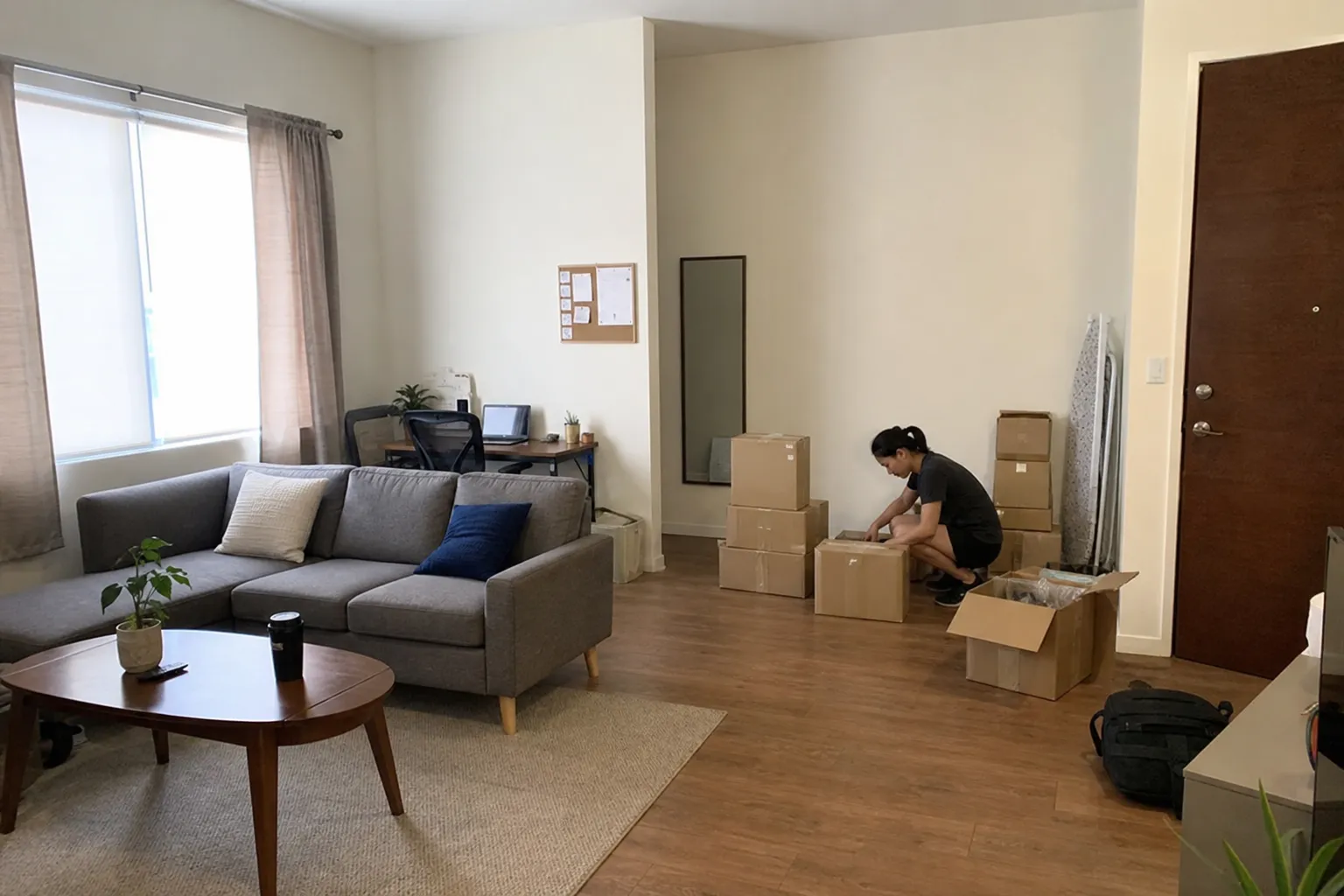 Person sorterar paket bland flyttkartonger i vardagsrummet, ett exempel på sambofällan när du driver eget.